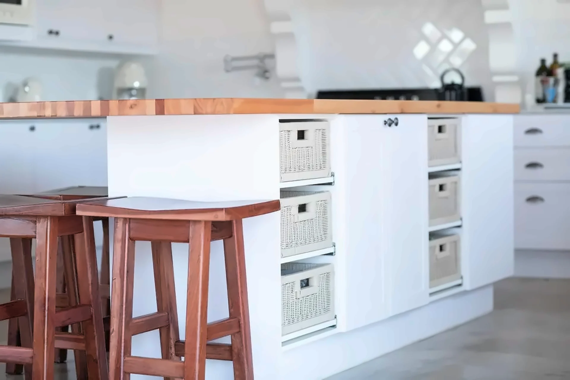 Butcher-block kitchen island with woven pull-out baskets, shaker doors and timber stools