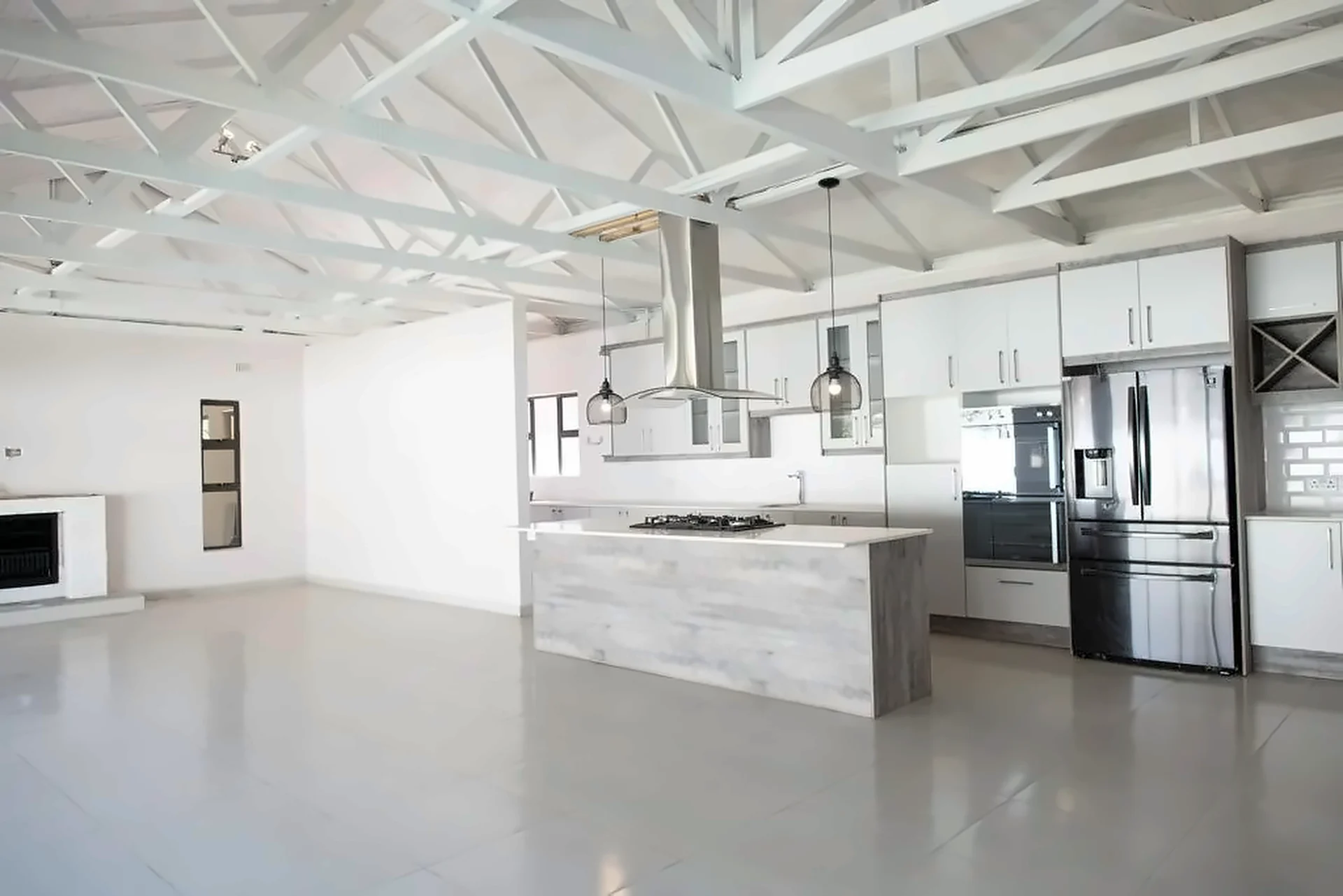 Open-plan kitchen with a long island, island extractor and wire pendant lights